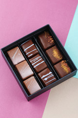 Assortment of luxury bonbons in box on colorful purple and blue background