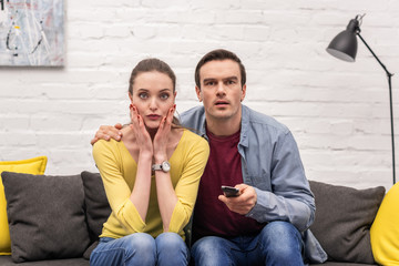 shocked adult couple watching tv together on couch