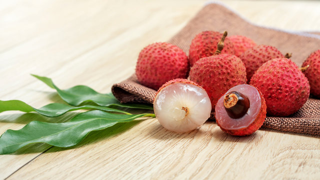 Red lychee fruit on a wooden table.