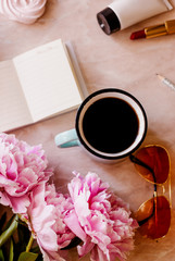 Beauty flat lay with a diary, cup of coffee, accessories and peonies on a marble background