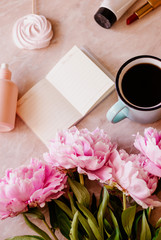 Beauty flat lay with a diary, cup of coffee, accessories and peonies on a marble background