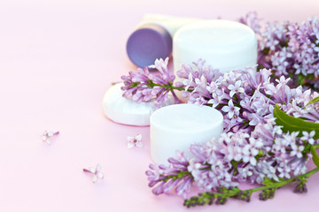 Plakat Natural floral fragrance cosmetics and spring blooming lilac. Jars with a rejuvenating cream and moisturizing flavored soap on a light pink background. Empty space for text