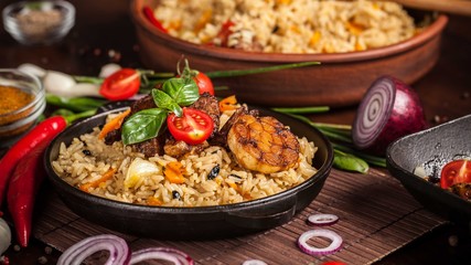 The concept of oriental cuisine. Homemade Uzbek pilaf from lamb served in cast iron cookware. Copy space.