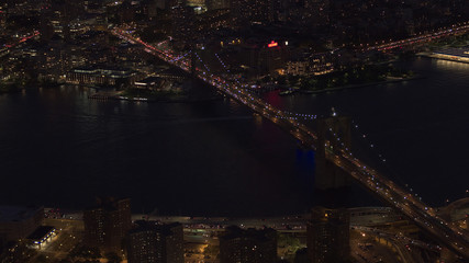 AERIAL: Iconic Brooklyn and Manhattan bridge above the East River lit at night