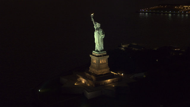 AERIAL, CLOSEUP: Iconic Statue od Liberty lit up at night shining in the dark