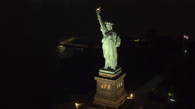 AERIAL, CLOSEUP: Famous Statue od Liberty lit up at night shining in the dark