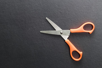 Yellow scissors on black background, top view.