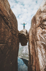Brave man traveler standing on Kjeragbolten raised hands Traveling in Norway Kjerag mountains summer vacations adventure success concept