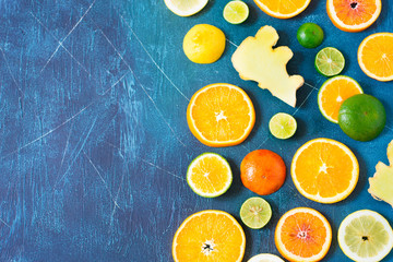 Citrus pattern on blue background with copy space. Assorted citrus fruits. Slices of orange, tangerine, lemon, lime and ginger. Top view.