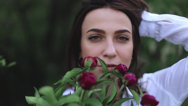 beautiful woman with pink peonies. girl smelling flowers and look sensual.