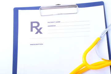 Closeup of medical stethoscope on a rx prescription, red heart isolated on white background