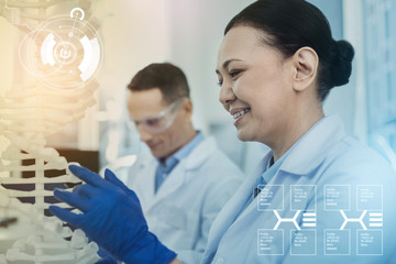 DNA analysis. Cheerful enthusiastic biologist wearing rubber gloves and smiling while looking at...