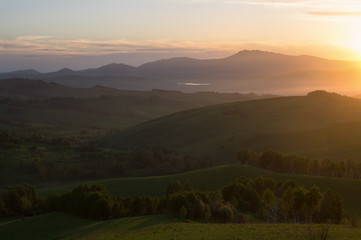 Green mountain landscape with illuminated sunset light valley and hills
