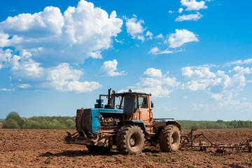 Obraz premium Tractor plowing a field on a sunny day. Preparing land for sowing. Agricultural works at farmlands. Agriculture industry