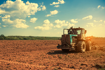 Tractor plowing a field at sunset. Preparing land for sowing. Agricultural works at farmlands. Agriculture industry