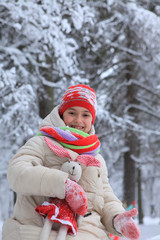 The frame depicts a winter forest, trees and pine trees. A child is playing with snow. Walk in the winter forest on vacation.