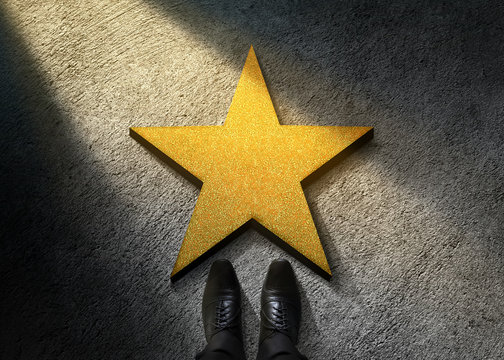 Success in Business or Personal Talent Concept. Top View of Businessman in Shiny Oxford Shoes standing in front of a Golden Star on the Dark Cement Floor