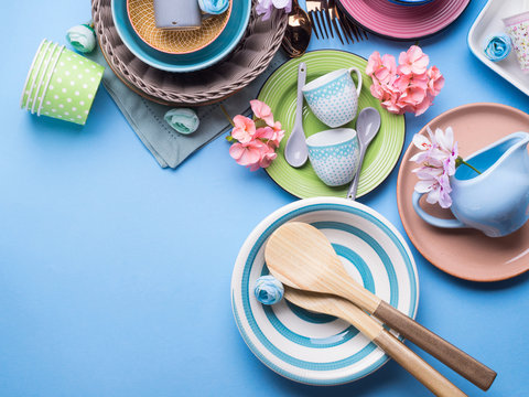 Tableware dish set on blue pastel background with flowers. Flat lay