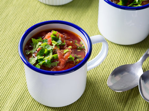 Russian beetroot soup borscht in enamel mugs on green cloth