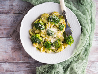 Orecchiette pasta with broccoli in white dish on wooden table. Easy recipe for lunch.