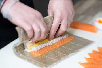 Obraz na płótnie Canvas Sushi master, cutting sushi rolls. Making sushi rolls. 