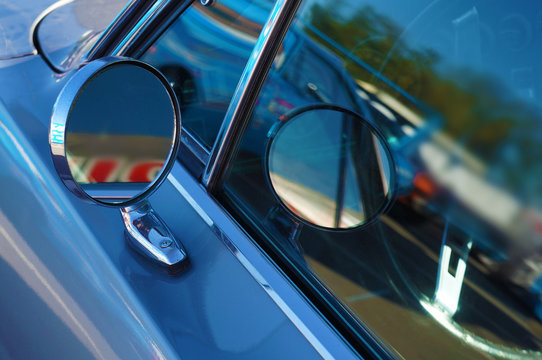 Side rear-view mirror and reflection in the window on blue retro car