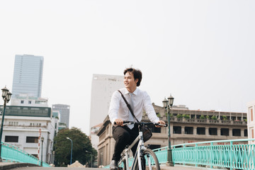 Going everywhere by his bike. Side view of young businessman looking forward while riding on his bicycle