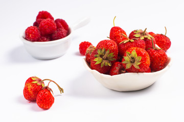 Summer fruits concept strawberry and rasberry in ceramic cup on white background with copy space