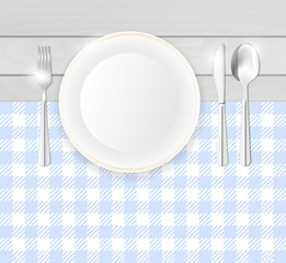 Porcelain plate and stainless cutlery on table with blue cloth