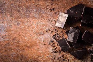 Black chocolate pieces on brown background. Top view. Copyspace