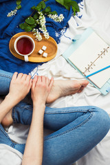 Flatlay with woman sitting in her bed with cup of tea, opened planner and flowers aside, social media mockup