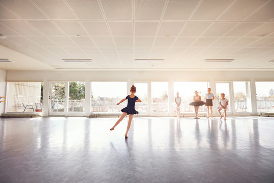 Little girl dancing ballet while group watching