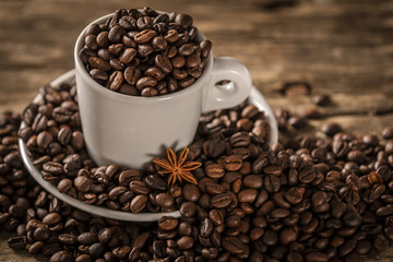 White cup covered coffee beans with star anise