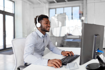 business, technology and people concept - happy african american businessman with headphones and...
