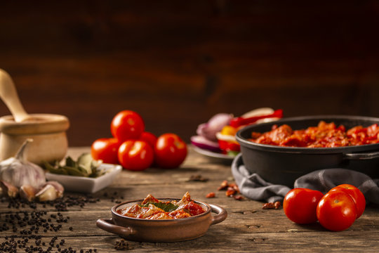 Meat and tomato meal with fresh vegetables and ingredients on dark background