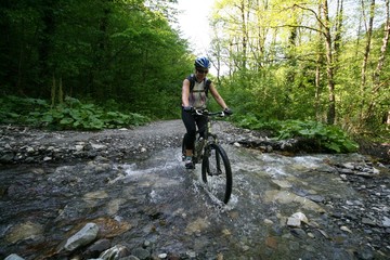 Fototapeta na wymiar Girl on a bike crosses a small river