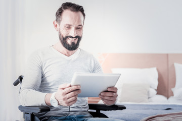 I am happy. Happy handicapped man sitting in a wheelchair and holding a tablet