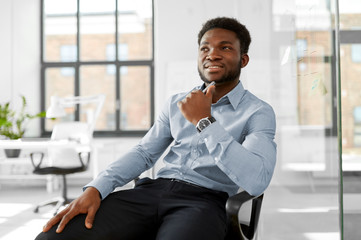 business and people concept - smiling african american businessman sitting on office chair