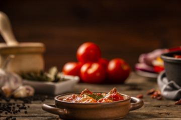 Meat and tomato meal with fresh vegetables and ingredients on dark background