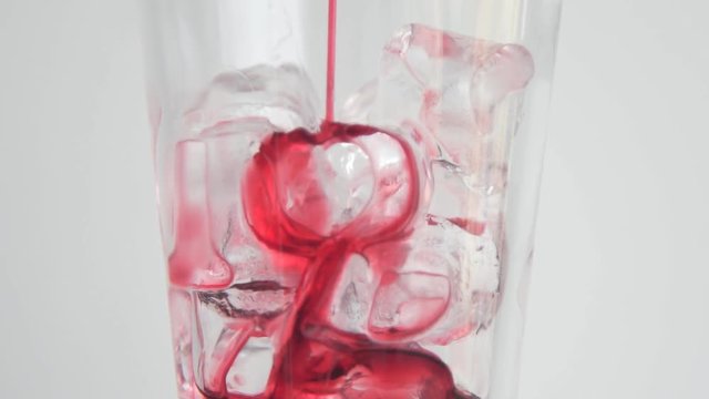 Adding red syrup to the glass with ice