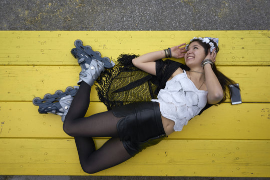 Smiling woman with inline skates lying on yellow table