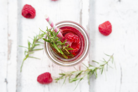 Glass bottle of homemade raspberry lemonade flavored with rosemary