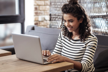 Professional freelancer. Positive happy woman sitting in the cafe while working on a laptop