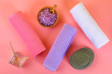 Spa on a pink pastel background. Towels, stones, aromamaslo, purple salt bath and pink flowers.