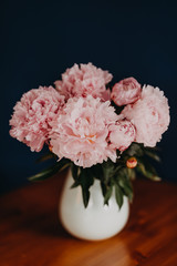 bouquet of beautiful pink peonys in a vase  on a dark blau background