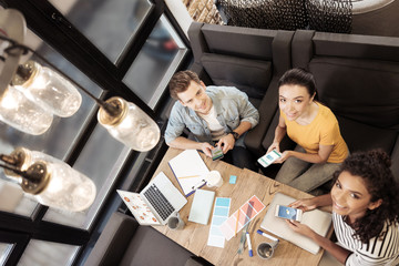 Pleasant mood. Top view of delighted young people looking at you while holding their gadgets