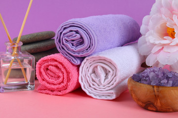 Obraz na płótnie Canvas Spa on a pink pastel background. Towels, stones, aromamaslo, purple salt bath and pink flowers.