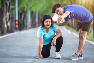 Trainer encouragement to fat woman who sitting on ground and point his hand to the target