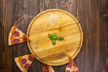 Pizza pepperoni with mozzarella cheese, salami and arugula on wooden background