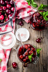 Homemade preserved cherry and mint jam, with fresh cherries on rustic old wooden background copy space above